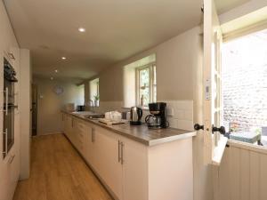 a kitchen with white cabinets and a counter top at Dell Cottage in Mundesley