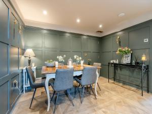 a dining room with green walls and a wooden table and chairs at Moat Farm in Tring