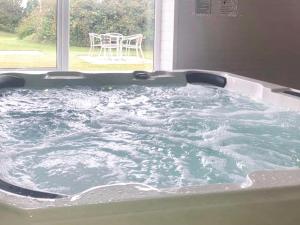 a bath tub filled with water in front of a window at Chaffinch Apartment - Uk49307 in Woolfardisworthy +12 photos