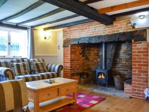 a living room with a brick fireplace and couches at Poona Cottage in Cadnam