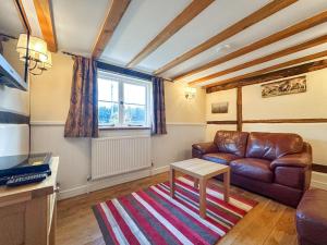 a living room with a leather couch and a table at Poona Cottage in Cadnam