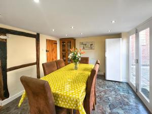 a dining room with a yellow table and chairs at Poona Cottage in Cadnam