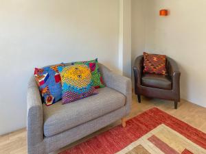 eine graue Couch mit bunten Kissen und einem Sessel in der Unterkunft Mallams Art House in Castletown