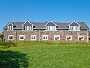 a brick building with white windows and a grass field at Goldfinch Apartment - Uk49296 in Woolfardisworthy