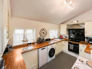 a kitchen with white cabinets and a washer and dryer at Butterfly Cottage in Maltby le Marsh