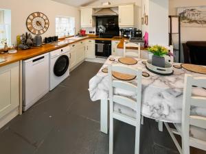 a kitchen with a table with chairs and a sink at Butterfly Cottage in Maltby le Marsh +4 photos