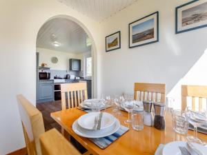 a dining room with a wooden table with wine glasses at Walled Cottage - Uk49097 in Inchnadamph
