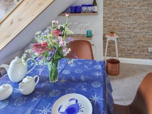 un tavolo con un vaso di fiori e piatti sopra di Issys Cottage a Helston