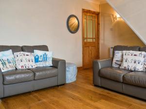 a living room with two leather couches and a table at Old Port Cottage in Hinderwell