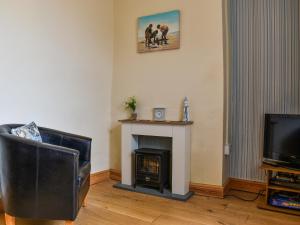 a living room with a fireplace and a television at Old Port Cottage in Hinderwell