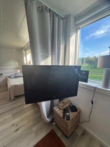 a television in a room with a bed and a window at Nyrenoverad 2-rummare med gratis laddning för elbil in Bankeryd