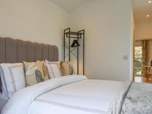 a bedroom with a bed with white sheets and pillows at Garden Cottage in Thornton Dale