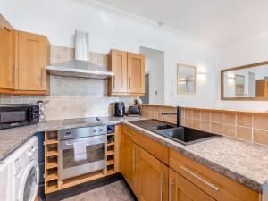 a kitchen with wooden cabinets and a sink and a stove at Riverview Retreat in Ebchester