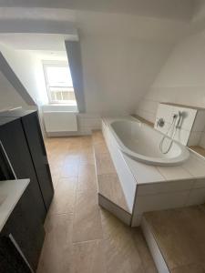 a white bathroom with a tub and a window at Vorverkauf Penthouse Loft Bamberg in Bamberg