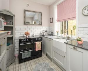 a kitchen with a black oven and a sink at Charming country cottage at a Victorian Station in Alnwick