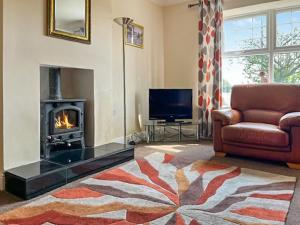 a living room with a fireplace and a couch and a television at Middle Farm in Durham