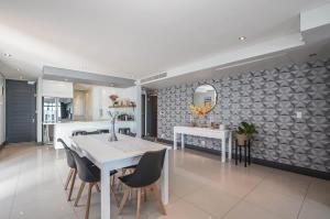 a kitchen and dining room with a white table and chairs at Executive Apartment with Ocean Views in Blouberg in Big Bay