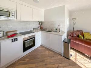 a kitchen with white cabinets and a red couch at Bramble - Uk49172 in Burgh le Marsh