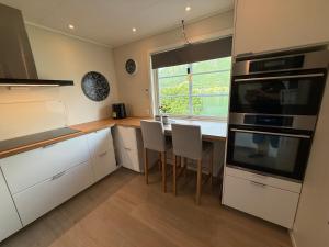a kitchen with white cabinets and a table with chairs at Vistdal Panoramic View in Myklebostad +4 photos
