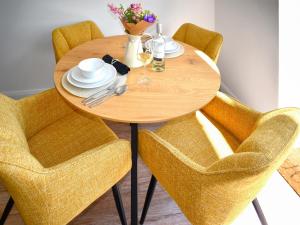 a wooden table with yellow chairs and a table with plates and glasses at The Old Hayloft - Uk49680 in Witheridge