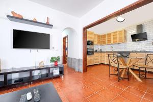a living room with a tv and a kitchen at Cocoteros Ocean View House in Guatiza