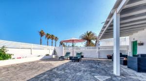 a patio with two chairs and an umbrella at Cocoteros Ocean View House in Guatiza