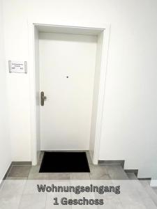 a hallway with a white door with a black door mat at Serviced Apartment " Nautilus " Papenburg Großer Balkon Einbauküche Neubau 74 qm Free Wifi 2 Schlafzimmer in Papenburg