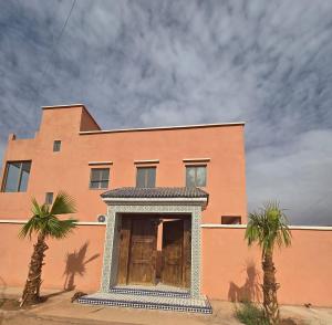 a building with two palm trees in front of it at Riad Gogo in Aït Benhaddou