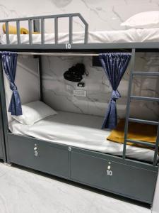 a bunk bed with blue curtains on a bunk bed at BASERA DORMITORY ANDHERI - Marol in Mumbai +9 photos