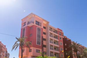 a pink building with palm trees in front of it at ZARI Boutique ApartHotel in Marrakesh