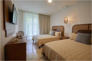 una camera d'albergo con due letti e una televisione di Apartamento Moderno en Playa Dorada Piscina & Playa a Puerto Plata Altre 12 foto