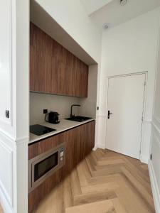 a kitchen with white walls and wooden cabinets at Suite Arche - Maison les Arcades au pied de la Gare de Charleville-Mézières in Charleville-Mézières