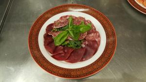 a plate of food with meat and greens on a table at Villa Sosnovy Bor in Zatoka