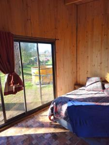 une chambre avec un lit et une grande fenêtre dans l'établissement Tierra de Volcanes, à Curacautín