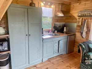 a kitchen with white cabinets and a sink in a cabin at Chalet nature in Grandrupt