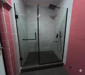 a glass shower in a bathroom with a pink wall at DimpleTravelodge in Lagos