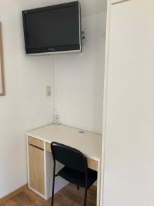 a desk with a chair and a television on a wall at Logies Villa Zilt in Koksijde