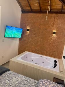 a bathroom with a tub with a tv on the wall at Riquezas de Lavras Novas - Chalé Safira in Lavras Novas
