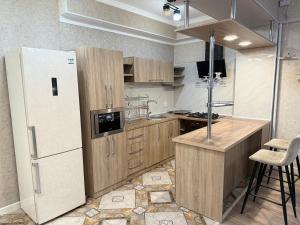a kitchen with wooden cabinets and a refrigerator at Bay tash in Bishkek