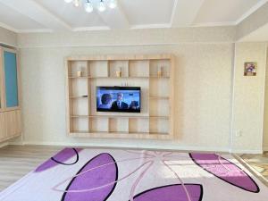 - un salon avec une télévision et un tapis violet dans l'établissement Bay tash, à Bishkek