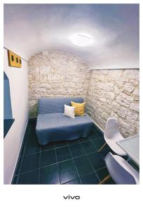a room with a blue couch and a stone wall at Tirella Home in Modica +58 photos