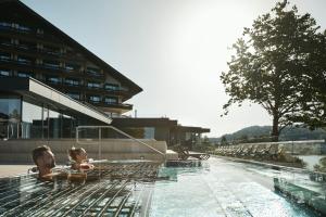 a man and a child are in a swimming pool at Hotel Karnerhof in Egg am Faaker See