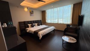 a bedroom with a bed and a chair and a window at Hotel Pixel House in Hubli