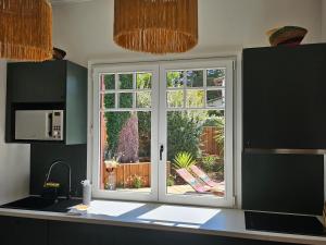 a kitchen with a window overlooking a garden at Maison de charme au Canon in Lège-Cap-Ferret