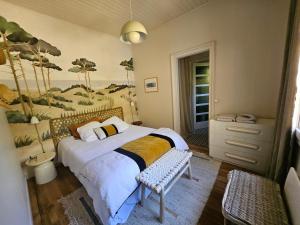 a bedroom with a bed with a painting on the wall at Maison de charme au Canon in Lège-Cap-Ferret