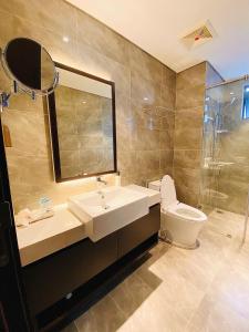 une salle de bain avec un lavabo, des toilettes et un miroir dans l'établissement The Sapphire Residence - AloTrip Homes, à Hạ Long