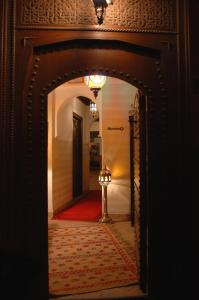 einen Torbogen in einen Flur mit einer Lampe in einem Raum in der Unterkunft Riad Aubrac in Marrakesch