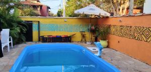 Ein Pool im Garten mit Tisch und Sonnenschirm in der Unterkunft Espacio chill hostel in Búzios