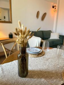 a vase with flowers sitting on a table with glasses at Studio Saint-Rémy-de-Provence centre in Saint-Rémy-de-Provence