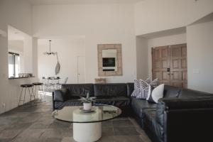 a living room with a black leather couch and a table at Aquarius By The Cohost Company in Yucca Valley